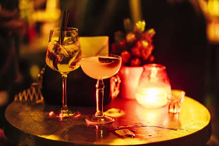 Zwei Cocktails und ein Kerzenglas auf einem Kupfertisch