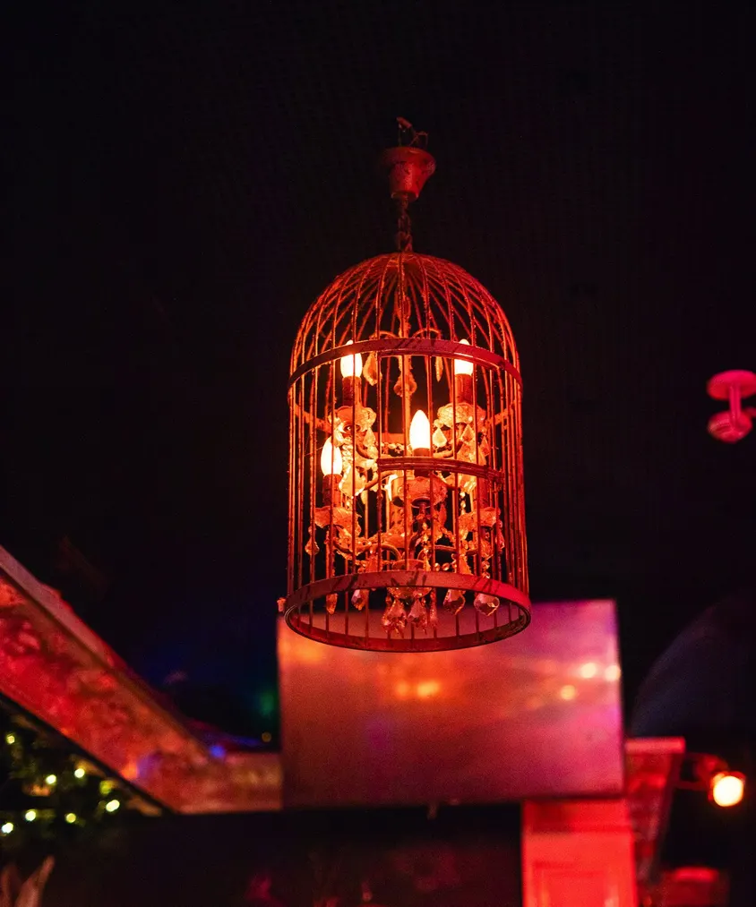 Beleuchteter Vogelkäfig als Lampe über dem Gastraum