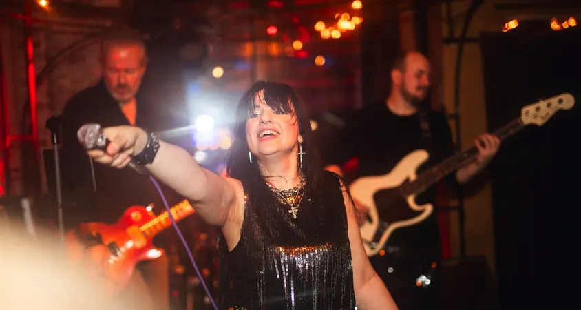 Sängerin streckt das Mikrofon ins Publikum, dahinter Gitarre und Bass